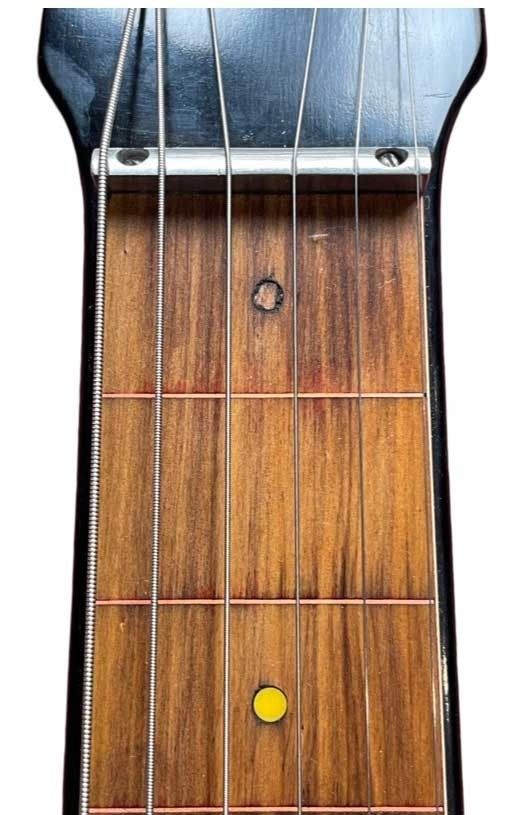 Nahaufnahme eines Gitarrenhalses mit Saiten und farbigen Markierungen